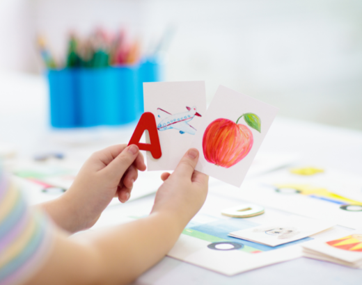 child holding flashcards apple airplane a